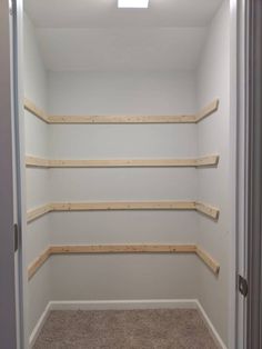 an empty walk - in closet with shelves and carpeted flooring on the side