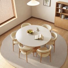 a round table with chairs and a book on it in a room that has hardwood floors