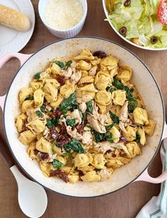 pasta with chicken and spinach in a skillet next to other dishes on the table