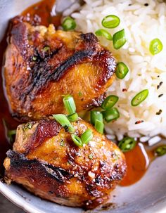 two pieces of chicken on top of rice in a bowl