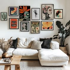 a living room filled with lots of pictures on the wall above a white couch and coffee table