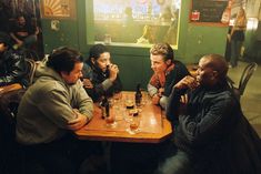 four men sitting at a table drinking beer and talking to each other in a restaurant