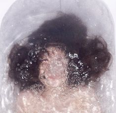 a woman with her hair in the air and water around her head, under a clear plastic cover