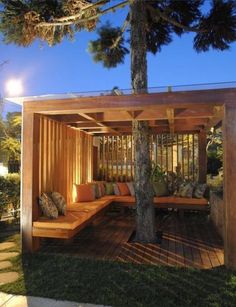 a wooden bench sitting under a tree on top of a lush green field at night