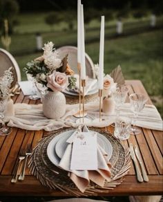 the table is set with candles, plates and napkins