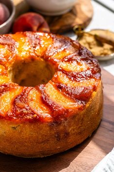 a pineapple upside down cake sitting on top of a wooden cutting board next to bowls of fruit