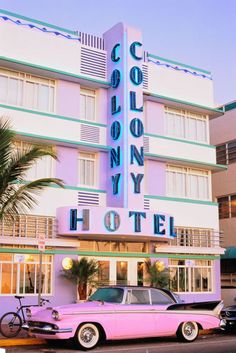 an old pink car parked in front of a hotel