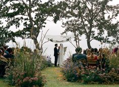 a bride and groom standing under an umbrella at their outdoor wedding ceremony on the lawn