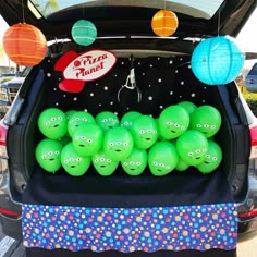 there are many green balls in the trunk of a car that is decorated with paper lanterns