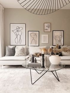 a living room filled with white furniture and pictures on the wall above it's coffee table