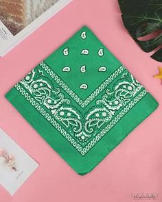 a green bandana laying on top of a pink table next to plants and pictures