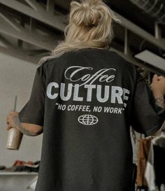 a woman in a black shirt is holding a coffee cup and looking at the ceiling