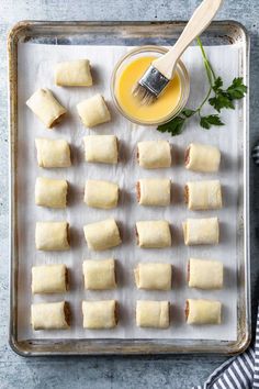 rolls on a baking sheet with butter and parsley next to them, ready to go into the oven