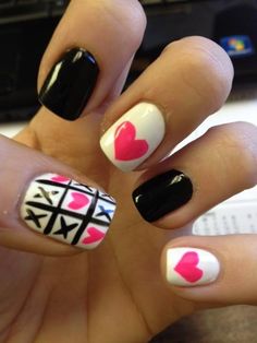 a woman's hand with black and white manies with pink hearts on them