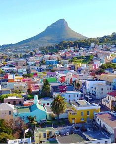 an aerial view of a city with colorful houses and mountains in the backgroud