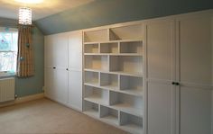 an empty room with white bookcases and a light hanging from the ceiling above it