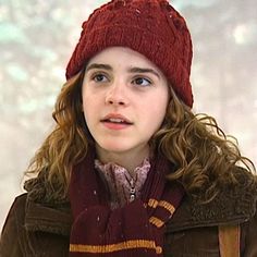 a young woman wearing a red hat and scarf is looking off to the side in front of a snowy background