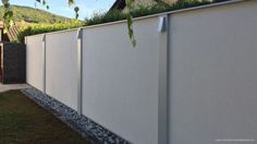 a white fence with grass growing on the top and bottom part, next to a house