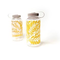 two glass jars with yellow leaves painted on them