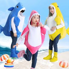 three children in shark costumes on the beach