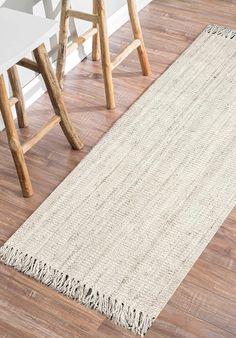 a white rug with fringes on the floor next to two stools and a table