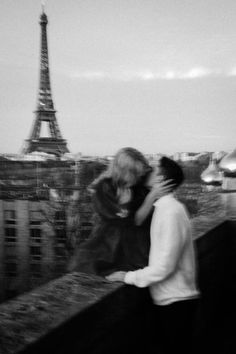 black and white photograph of two people kissing in front of the eiffel tower