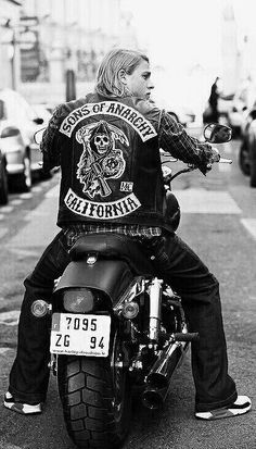 a man riding on the back of a motorcycle down a street