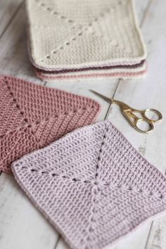 crocheted dishcloths and scissors on a white wooden table with pink and cream colors