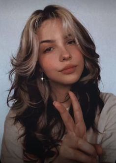 a young woman making the v sign with her hand while wearing a t - shirt