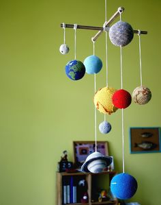 a crocheted mobile with balls hanging from it's sides in a green room