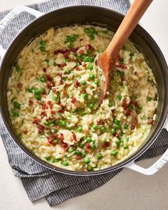 a pot filled with rice and peas on top of a towel next to a wooden spoon