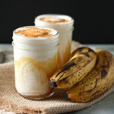 there are three jars with food in them on the table next to two ripe bananas