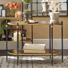 a table with flowers, candles and books on it in front of a wall mirror