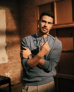 a man standing in front of a brick wall with his arms crossed