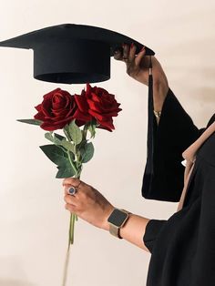 a woman holding a bouquet of roses in front of her graduation cap