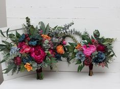 two bouquets of flowers are sitting on a white bench with greenery and foliage