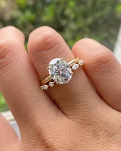 a woman's hand holding a ring with a diamond in the middle and two diamonds on it