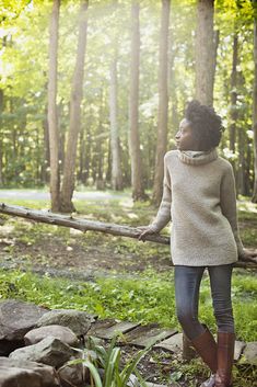 a woman walking in the woods carrying a log