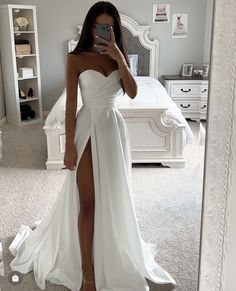 a woman taking a selfie in a white dress with her legs slited up