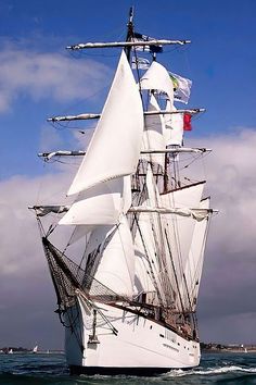 a large white sail boat sailing in the ocean