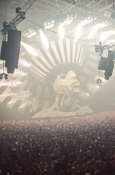 a large group of people in front of a stage with lights and sound equipment on it