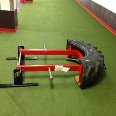 a red bike frame sitting on top of a green floor next to a black tire