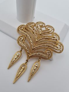 An extremely rare 1960s Monet brooch, in exceptional vintage condition.  This will make a stunning addition to your collection. The design is simultaneously classic and modern, which makes it such an intriguing piece, to be treasured for decades to come.  Signed Monet, with a secure safety clasp. 7.6cm x 6.4cm. -------------------- 🏆About the Designer: Vintage Monet jewellery is prized by collectors because of its high quality and design. The triple-plating manufacturing process ensures that Mo Ornate Gold Brooch With Intricate Design, Ornate Gold Brooches With Intricate Design, Antique Gold Brooches With Intricate Design, Antique Gold Brooch With Intricate Design, Vintage Yellow Gold Filigree Brooches, Gold Filigree Ornate Brooches, Ornate Gold Filigree Brooches, Elegant Gold Filigree Brooches, Gold Filigree Brooches For Wedding