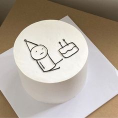 a white cake with black writing on it sitting on top of a piece of paper