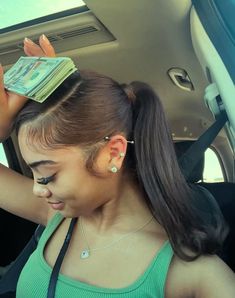 a woman holding money in her hand while sitting in the back seat of a car