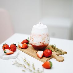 strawberries sit on a cutting board next to a bowl of yogurt