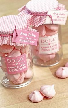 small jars filled with pink macaroni and cheesecakes on a wooden table