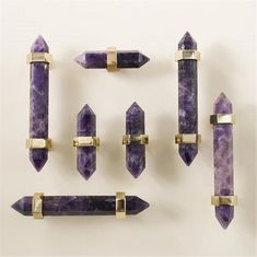 an assortment of amethysts and brass handles on a white surface, including one purple stone