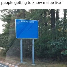 a blue street sign sitting on the side of a road next to a lush green forest