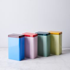 three different colored trash cans on a white surface